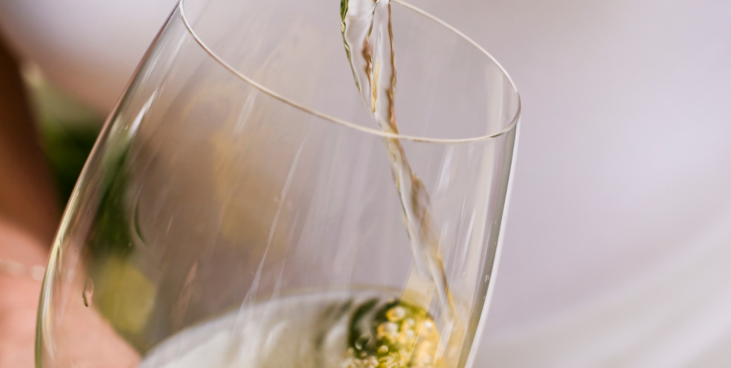 Close-up van een glas waarin in witte wijn geschonken wordt
