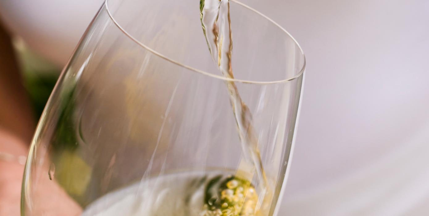 Close-up van een glas waarin in witte wijn geschonken wordt
